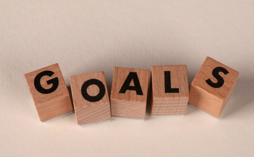 Aligned wooden blocks spelling 'Goals' symbolize target achievement and ambition.